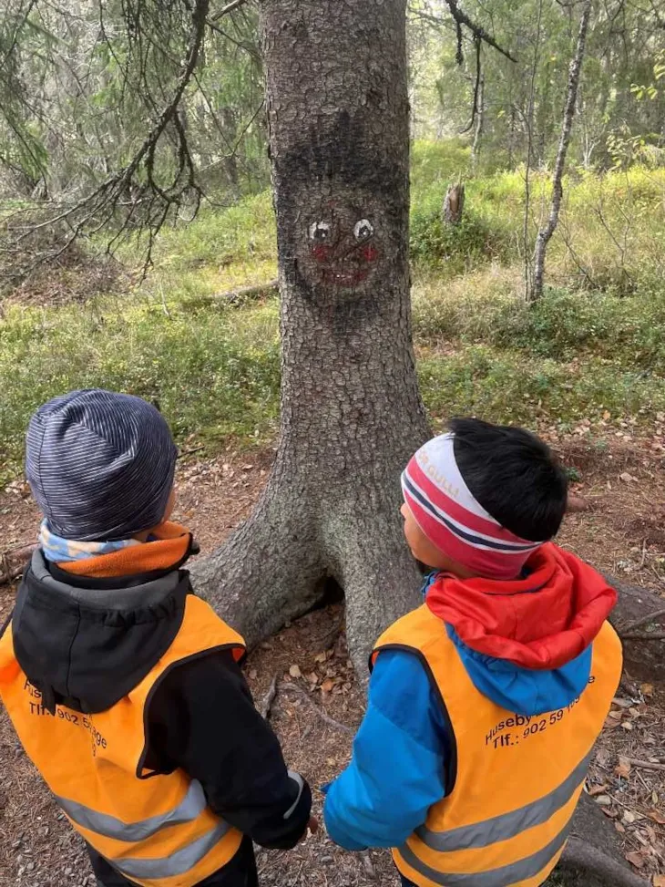 Barn som ser p&aring; et tre med p&aring;tegnet ansikt