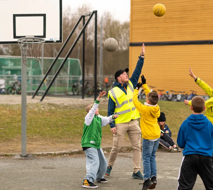 Kontaktlærer Sondre Brekke Valmork som spiller basketball med barn i skolegården