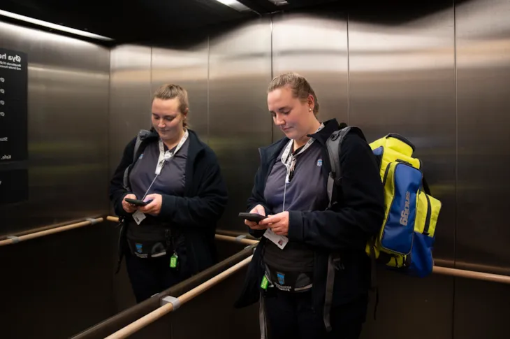 Synne jobber på mobilen i heisen på vei til parkeringsgarasjen.