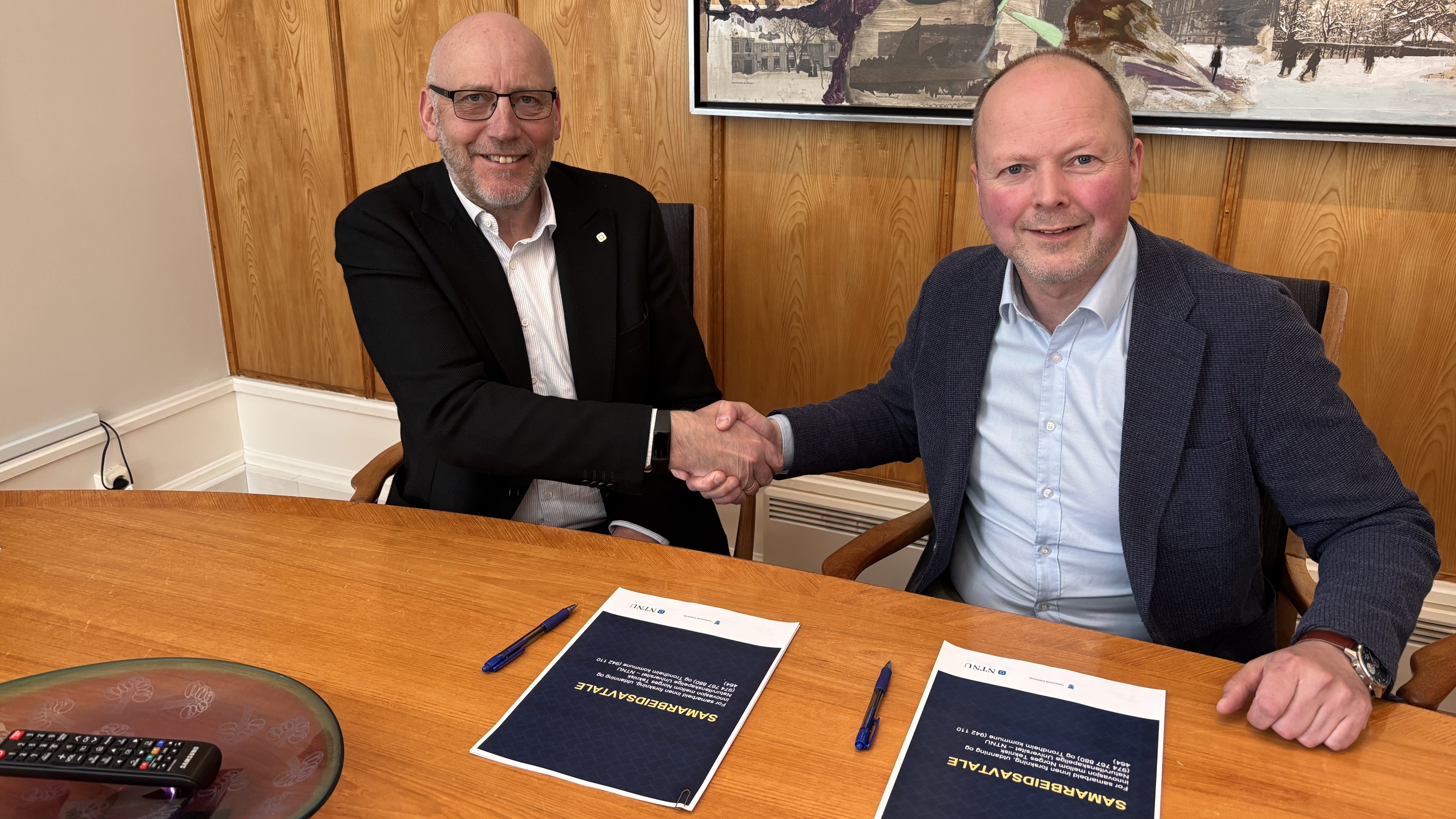 Bilde viser Tor Grande og Kjetil Reinskou som gjør ett håndtrykk i forbindelse med signeringen av samarbeidsavtale