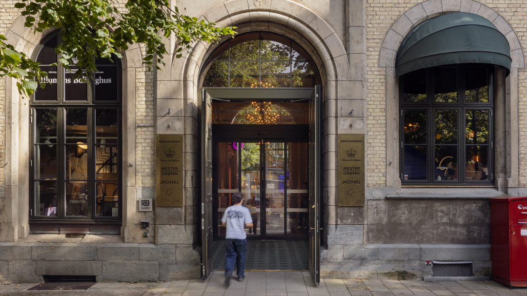 Eldre murbygning med en stor åpen port som fører inn til butikker