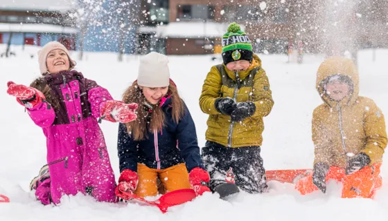Fire barneskoleelever som leker seg ute i snøen.