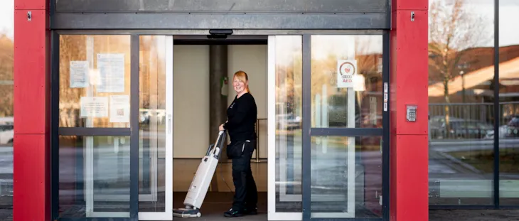 Foto av renholdsoperatør Maia Berg med tepperenser i i inngangspartiet på Spongdal skole