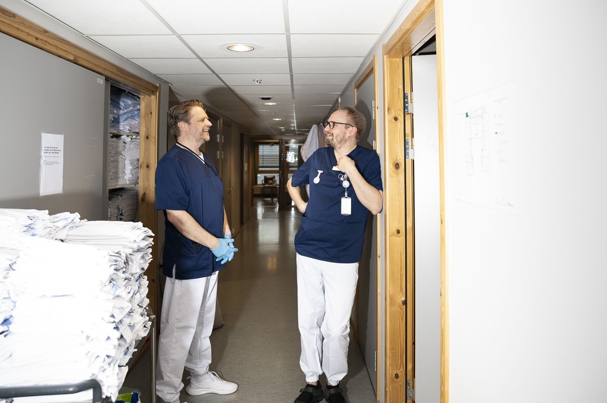 Helsefagarbeider Lars Erik sl&aring;r av en lystig prat med en kollega i gangen