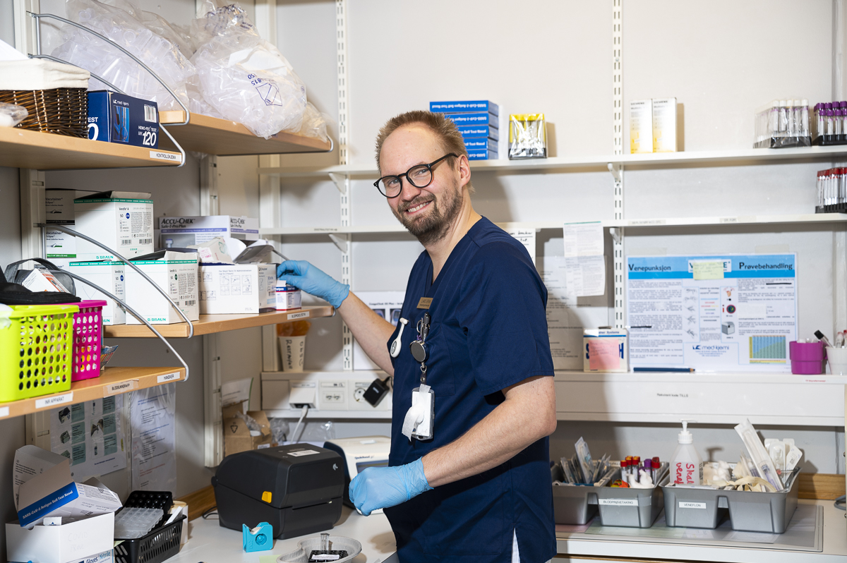 Helsefagarbeider Lars Erik p&aring; et lagerrom omgitt av hyller med medisiner.