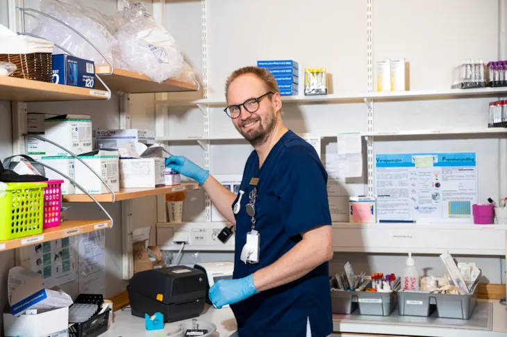 Helsefagarbeider Lars Erik p&aring; et lagerrom omgitt av hyller med medisiner.