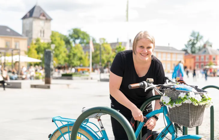 Prosjektleder Elin Øvren parkerer og låser sykkelen. Torvet er i bakgrunnen.