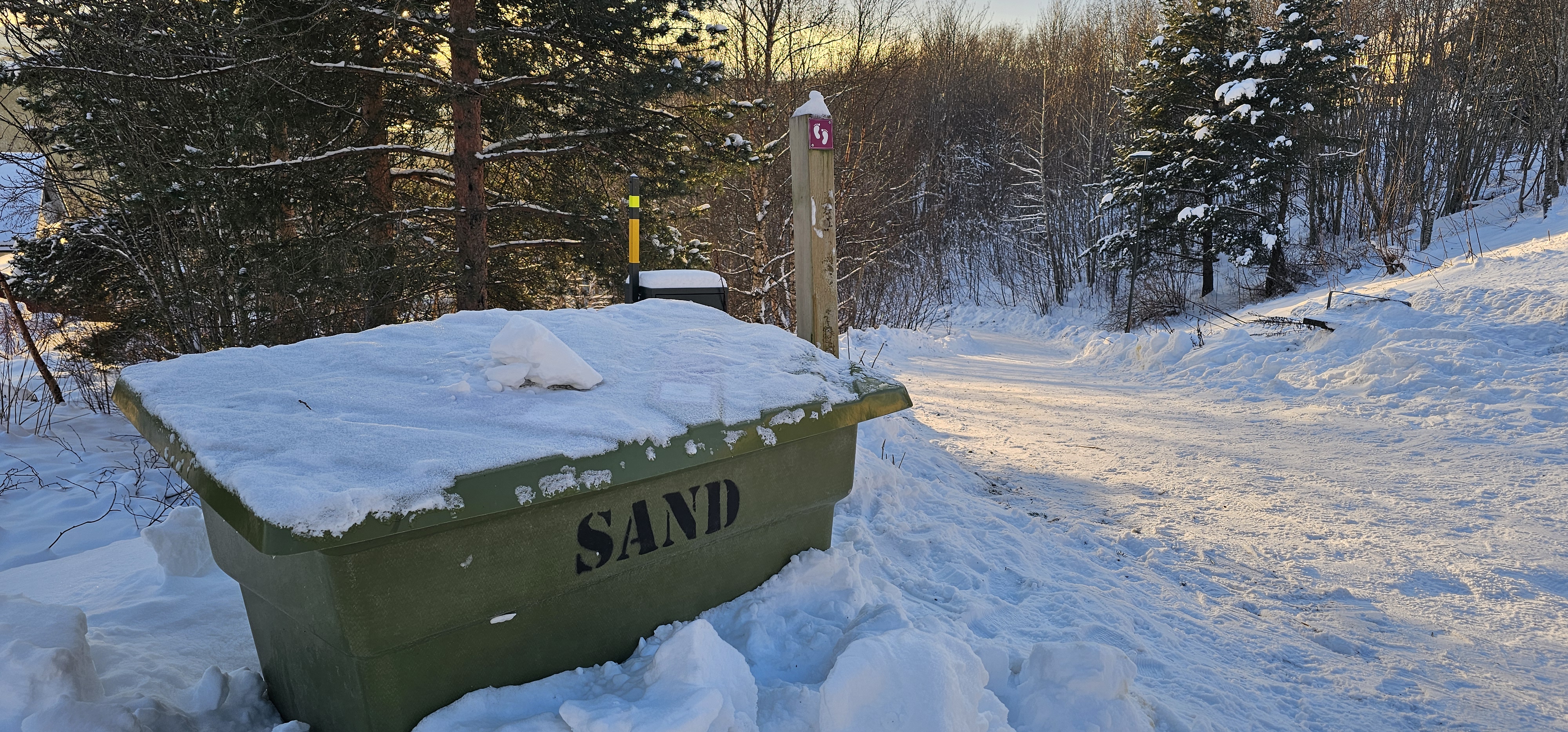 kasse med str&oslash;sand og skilt som viser en snarvei