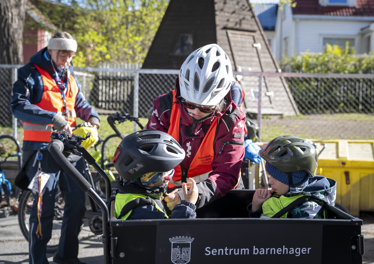 Ansatt med hjelm fester barn i sykkelvogn