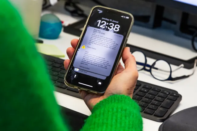 En person holder opp en iphone der det er et varsel der det står "dette er en test"