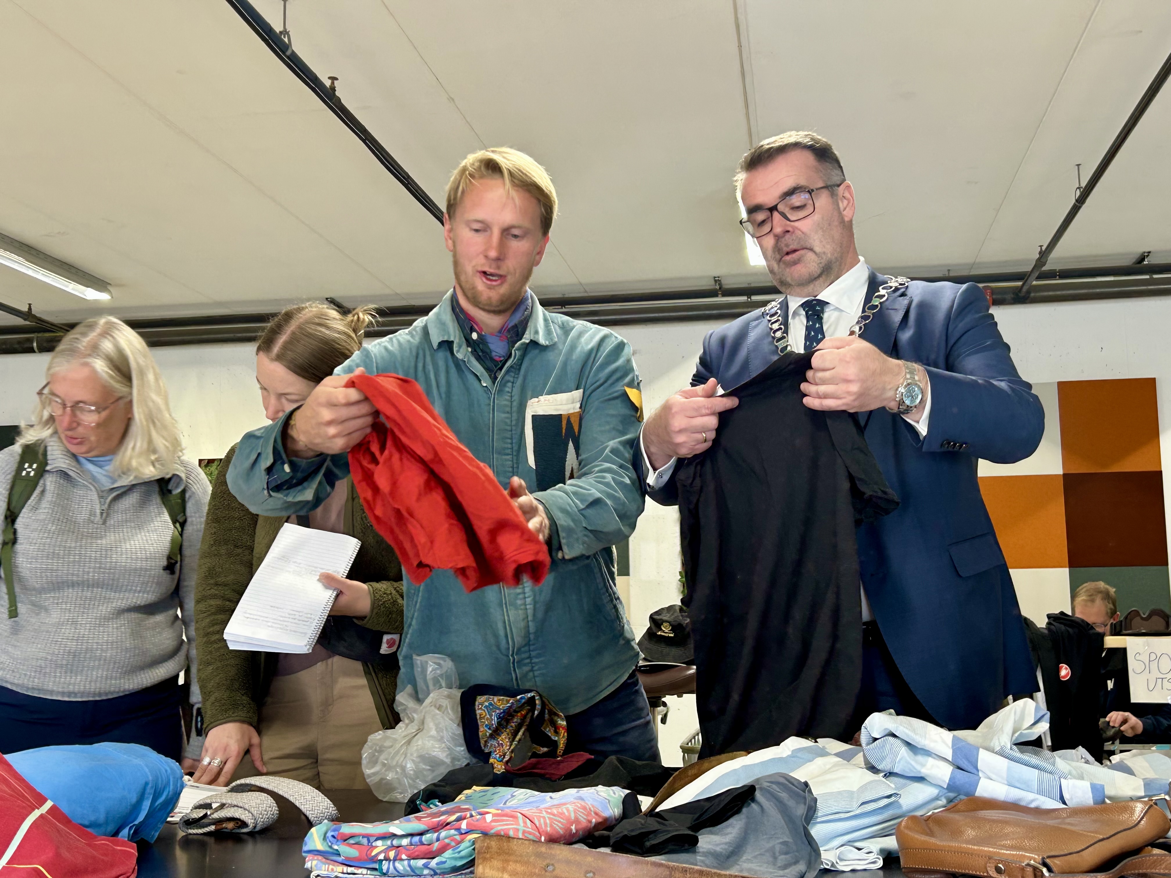 To menn står og sorterer tøy