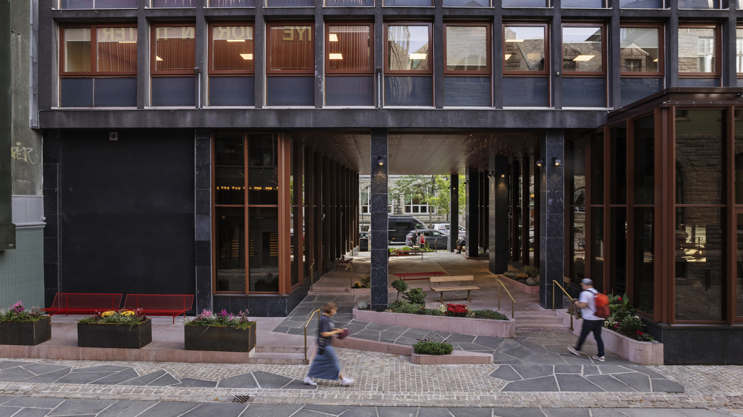 Bilde av en åpen passasje gjennom et kontorbygg. Det går ramp og trapp opp til passasjens gulv.