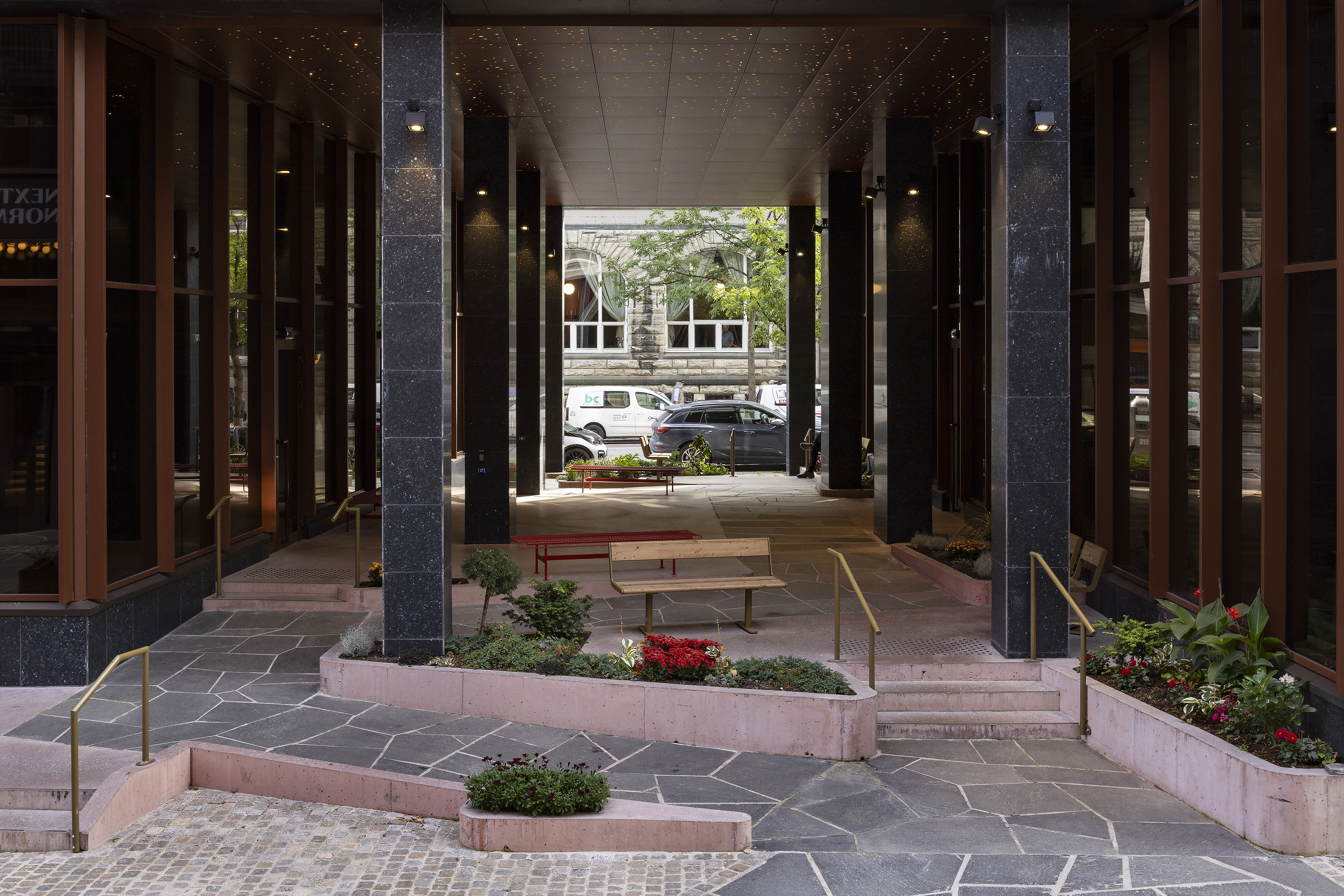 Rampe og trapp som f&oslash;rer opp i passasjen, rampen er i skifer og kanter i lys r&oslash;d betong