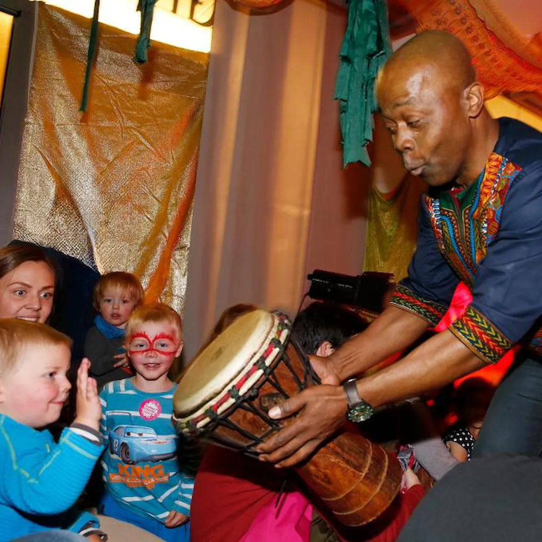 Musiker Raymond Seraba på verkstedet Mini-Afrika viser fram en congastromme til en gruppe barn.