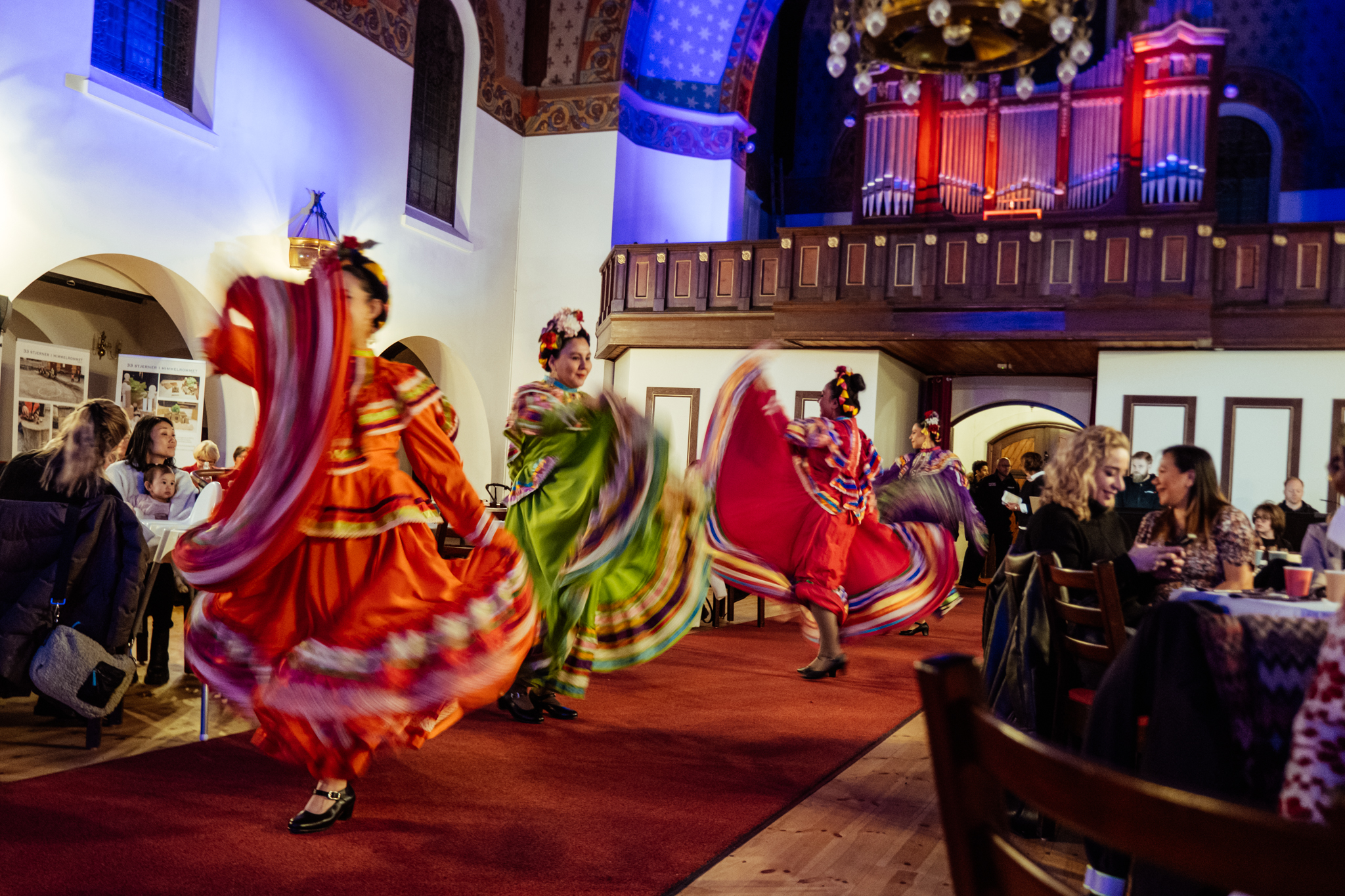 Kvinner som danser på en scene i fargerike folkedrakter.