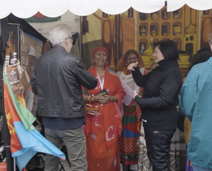 En kvinner tegnspårktolker for en mann ved en markedsbod.