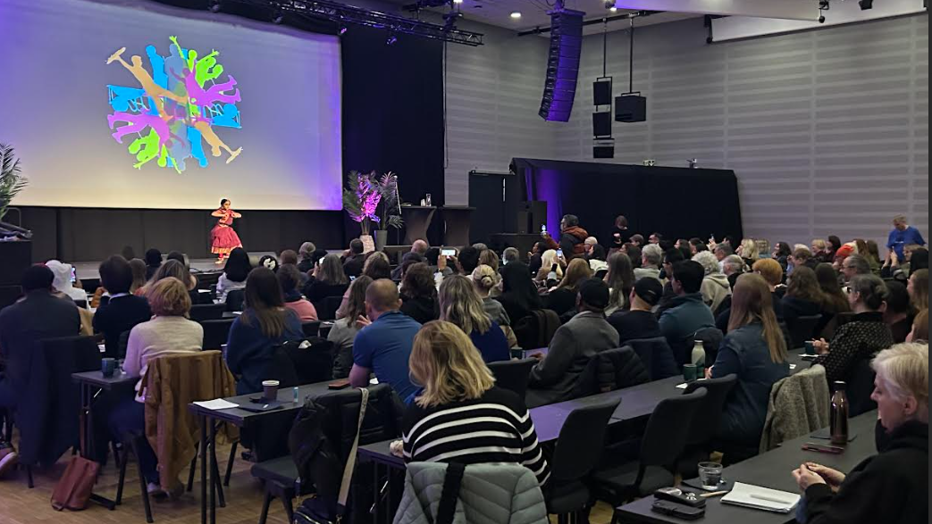 En konferansesal med mange deltakere foran en scene