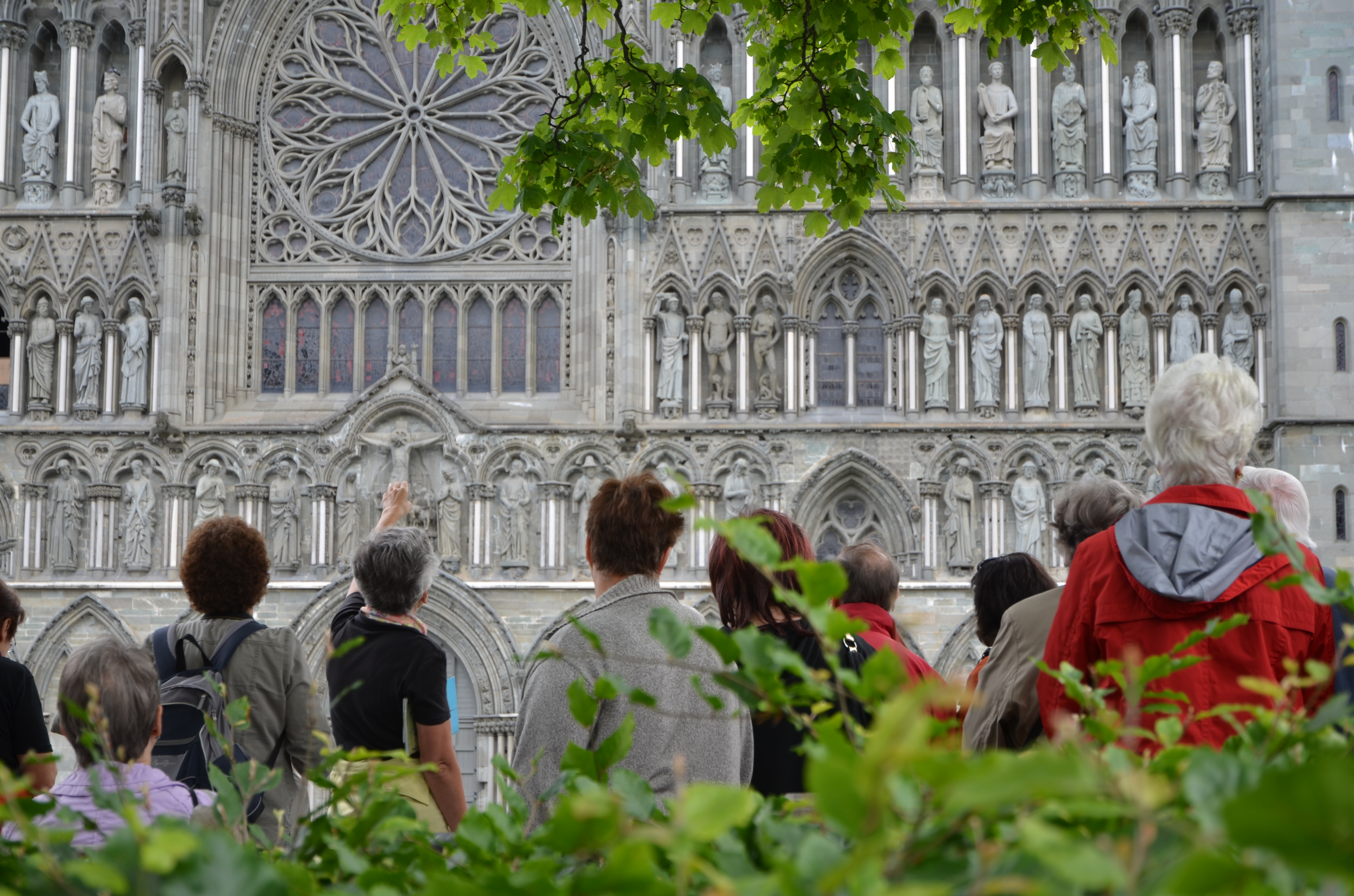 Turister som står og speider mot Vestfronten av Nidaros domkirke.