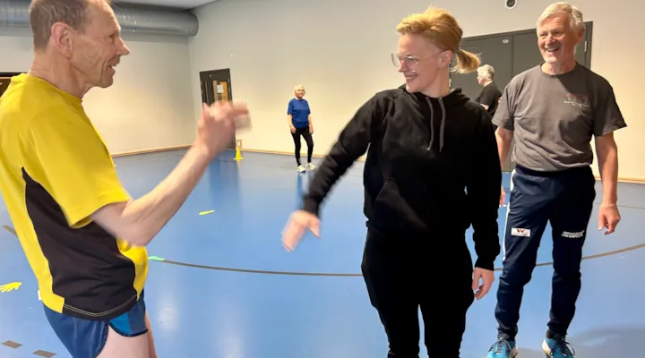 Gruppetrening i Myrahallen. Instruktør gir high-five til en av deltagerne.