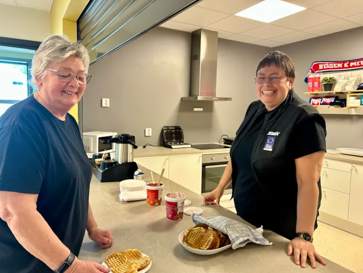 Rita Ottervik står bak disken og serverer kaffe til en av deltagernerverer i kafeen til By