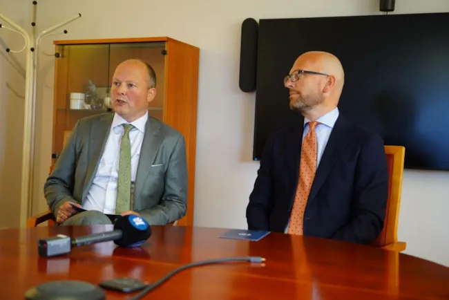 Kjetil Reinskou og Kristian Dahlberg Hauge sitter ved et bord med en mikron på bordet