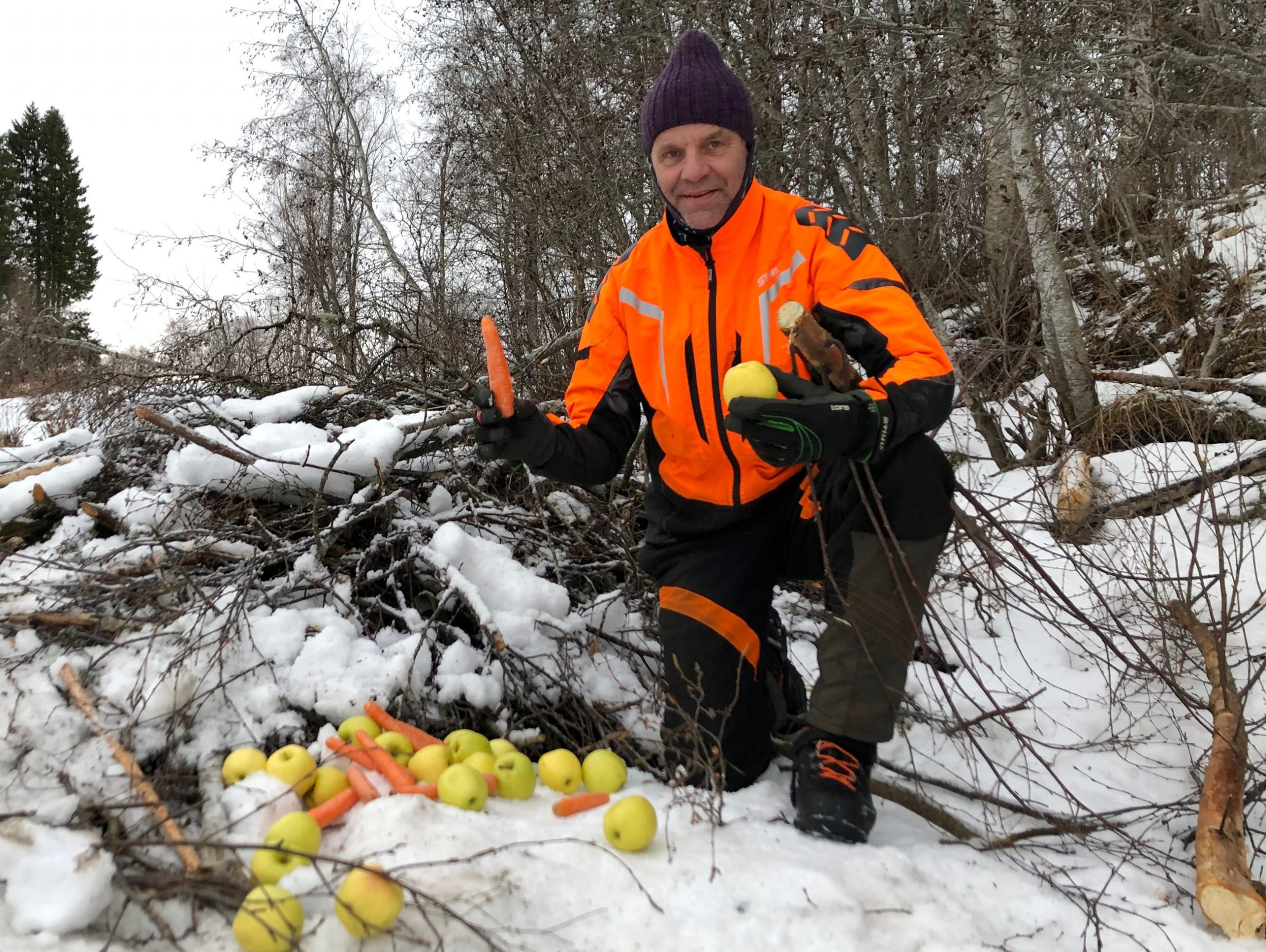 Mann sittende i skogen bak frukt og grønnsaker