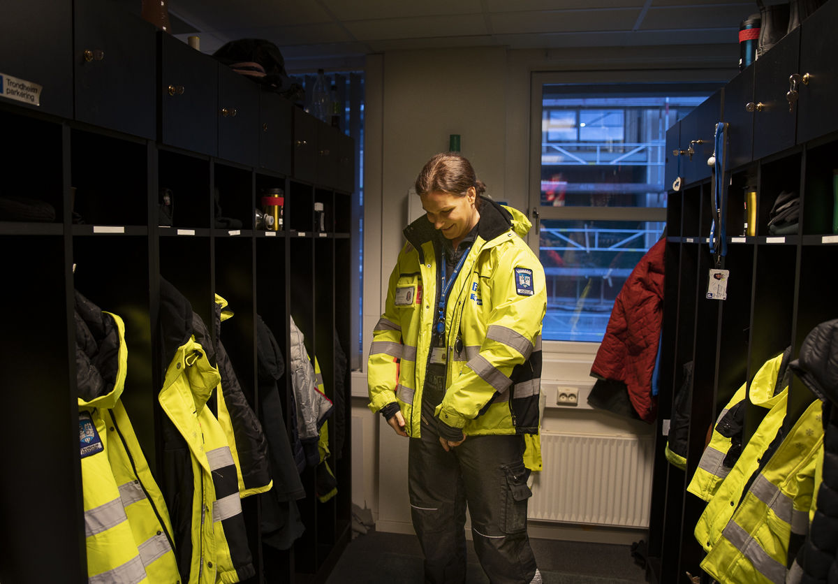 Foto av trafikkbetjent Marie i garderoben der hun kler seg om f&oslash;r dagens skift. Rundt henne er mange garderobeskap med uniformer.