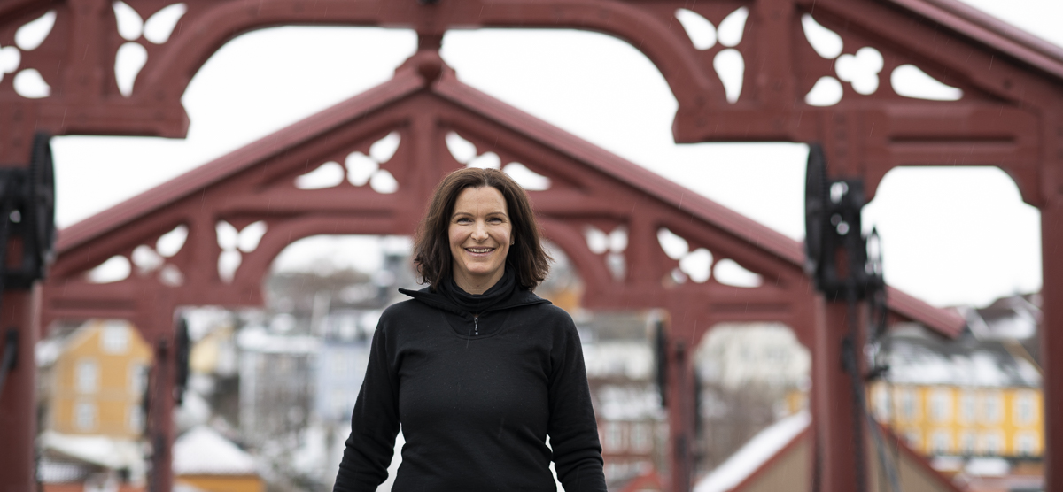 Foto av trafikkbetjent Marie i sivile kl&aelig;r under Lykkens portal p&aring; Gamle Bybro. I bakgrunnen skimtes Brobakken og deler av Bakklandet.