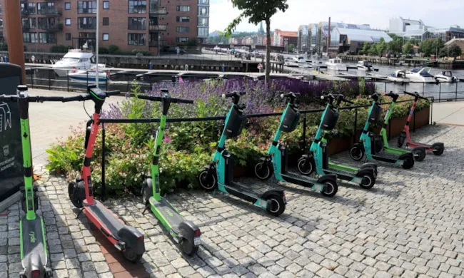 elsparkesykler som står parkert ved et stativ