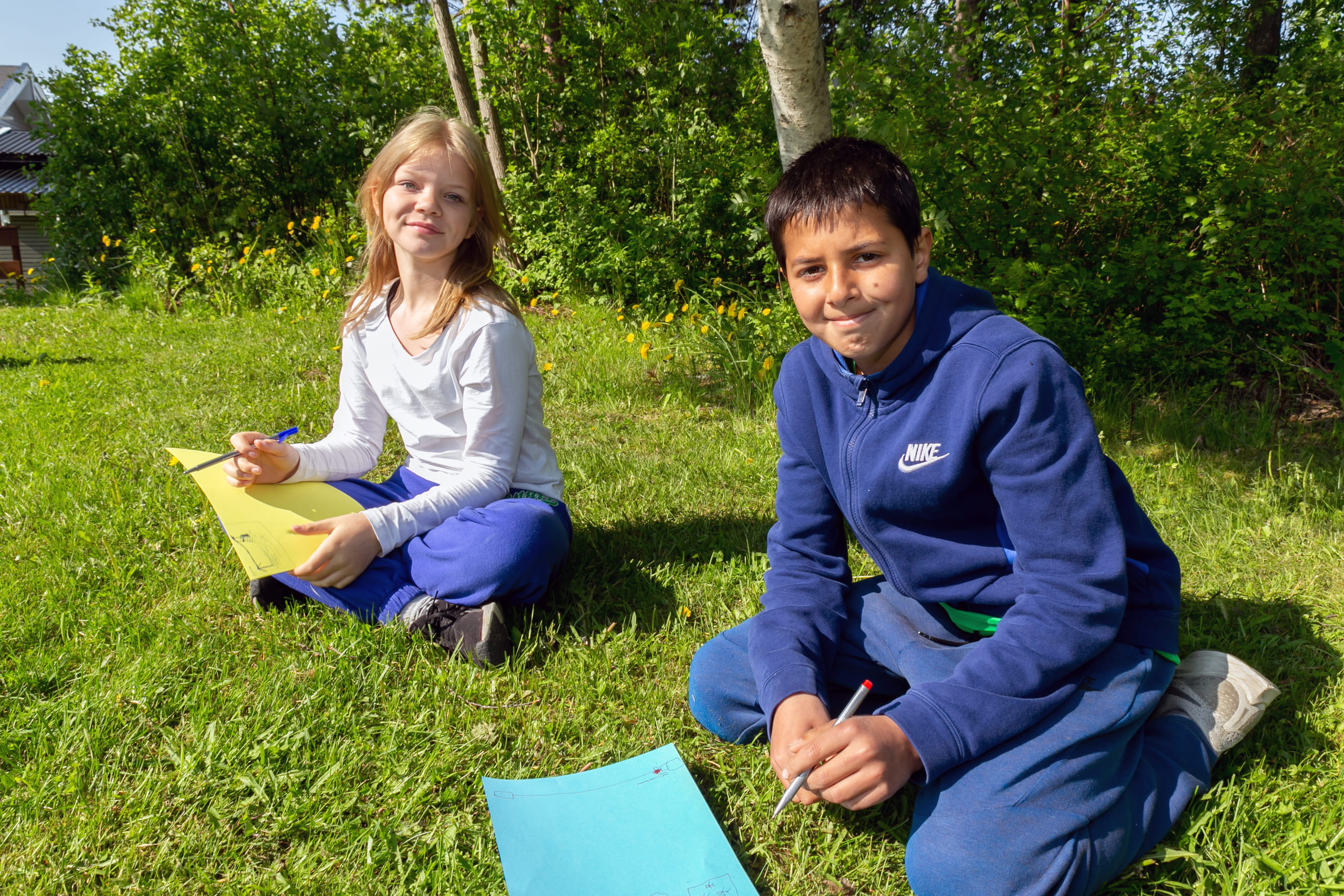 To barn som sitter på ei gressplen