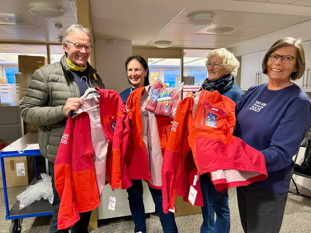 En mann og tre kvinner viser fram jakkene som de frivillige under Ski-VM skal bruke