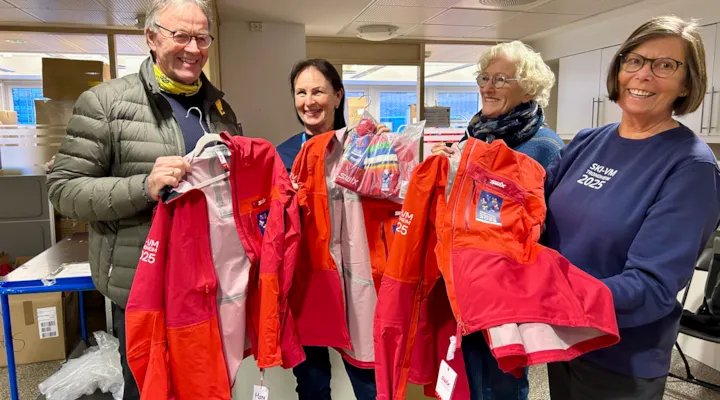 En mann og tre kvinner viser fram jakkene som de frivillige under Ski-VM skal bruke