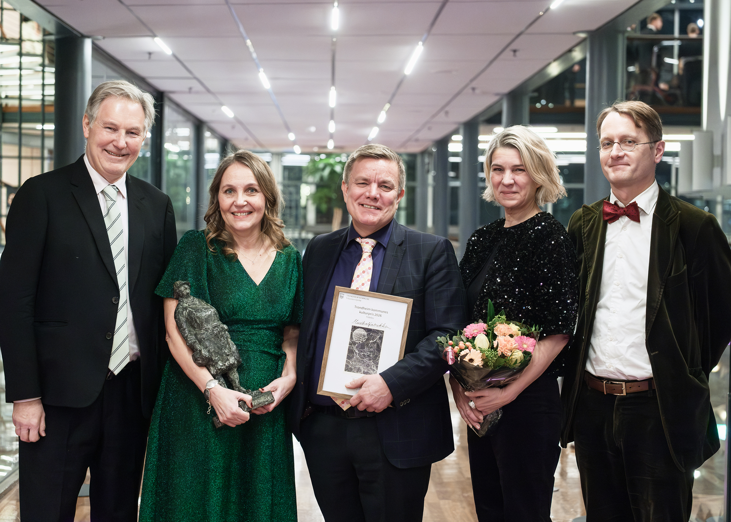 Alle fotografert sammen, med priser og blomster. ser i kamera.