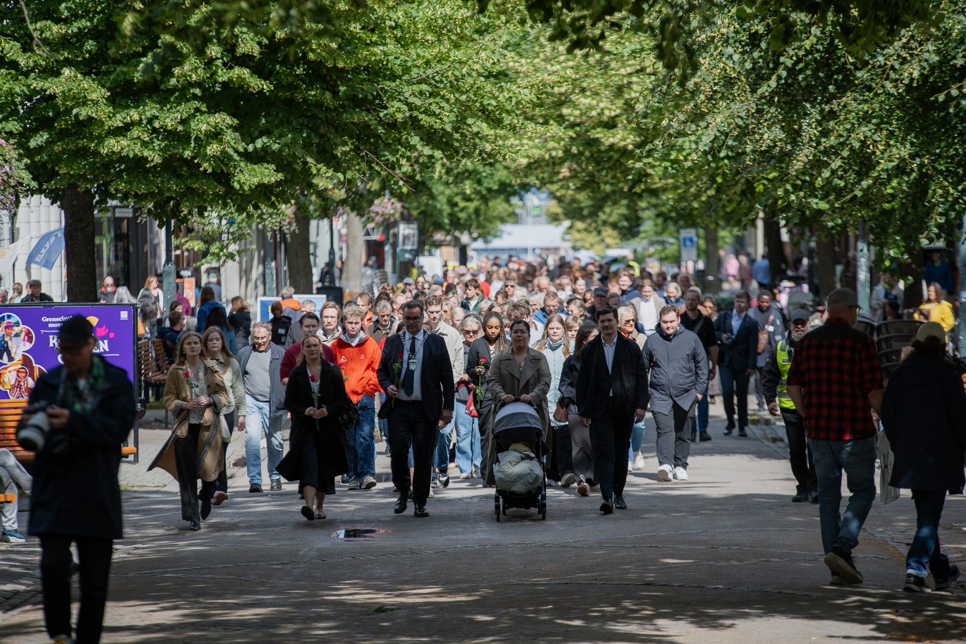 Mange mennesker går i rekker med roser i hånden