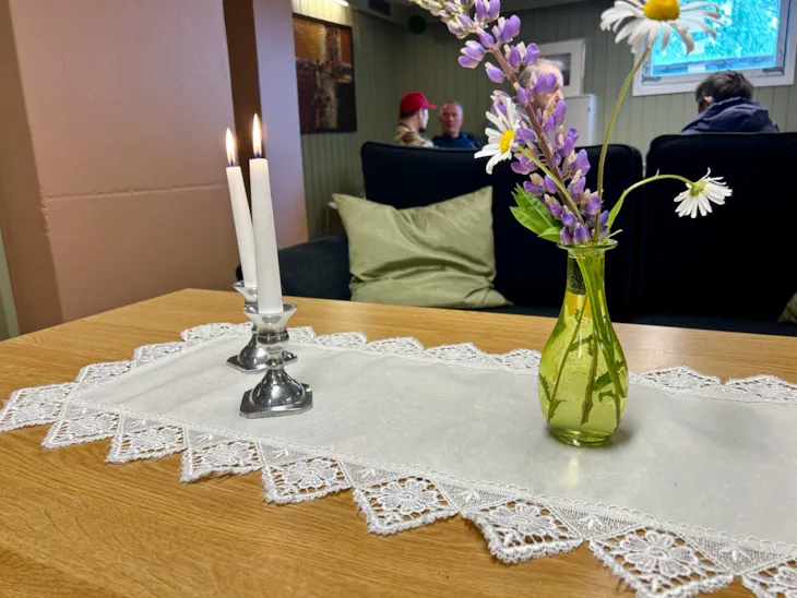 Tente lys og blomster pynter opp på bordet