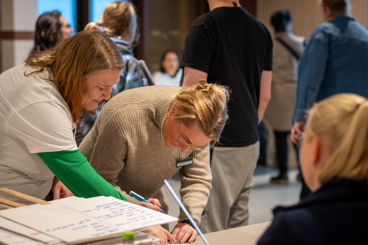 To damer skriver under på et papir.