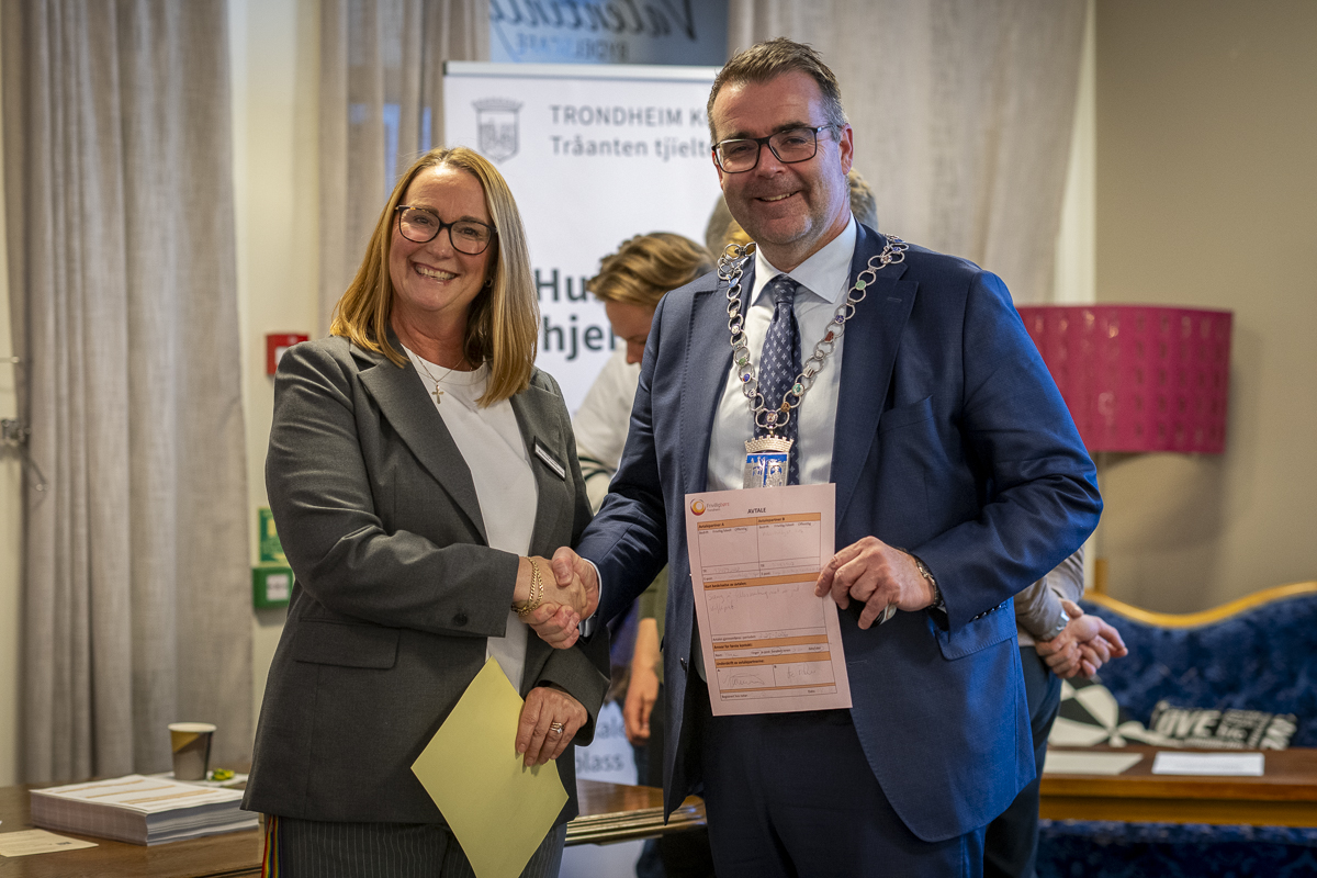 Kvinne og mann holder frem avtale og smiler.