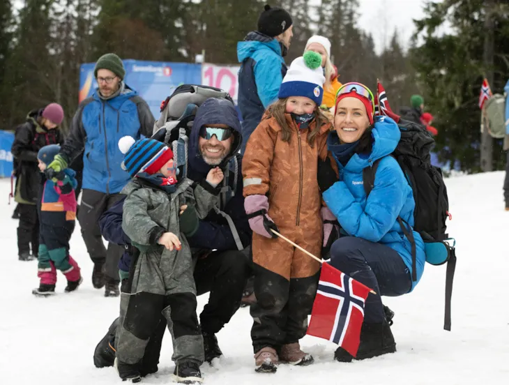 En familie med mor, far, gutt og jente smiler til kamera.