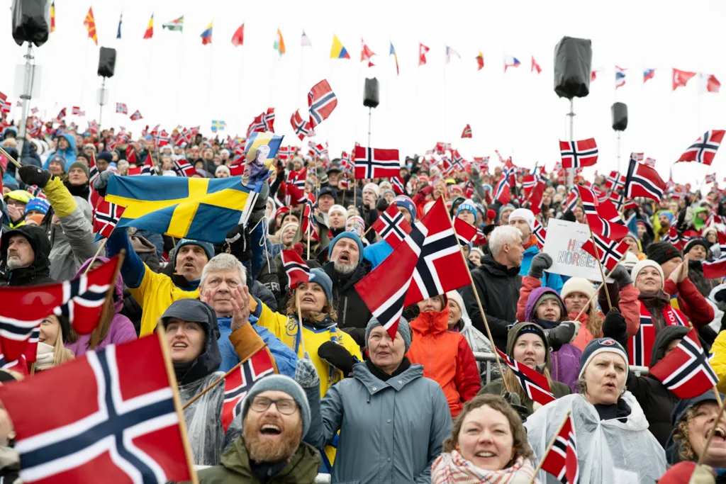 En stor folkemengde med norske og svenske flagg jubler fra en tribune.