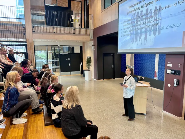 Line Fjørstad holder tale til et fullsatt auditorium med skoleelever.