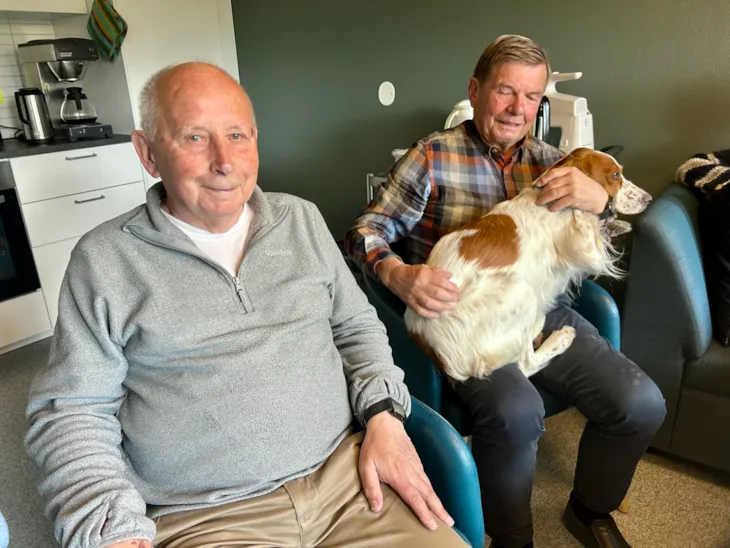 To mannlige pårørende. Den ene med hund på fanget. mep