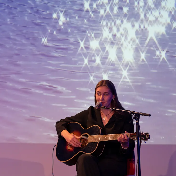 Sara Fjeldvær synger og spiller gitar på scenen.