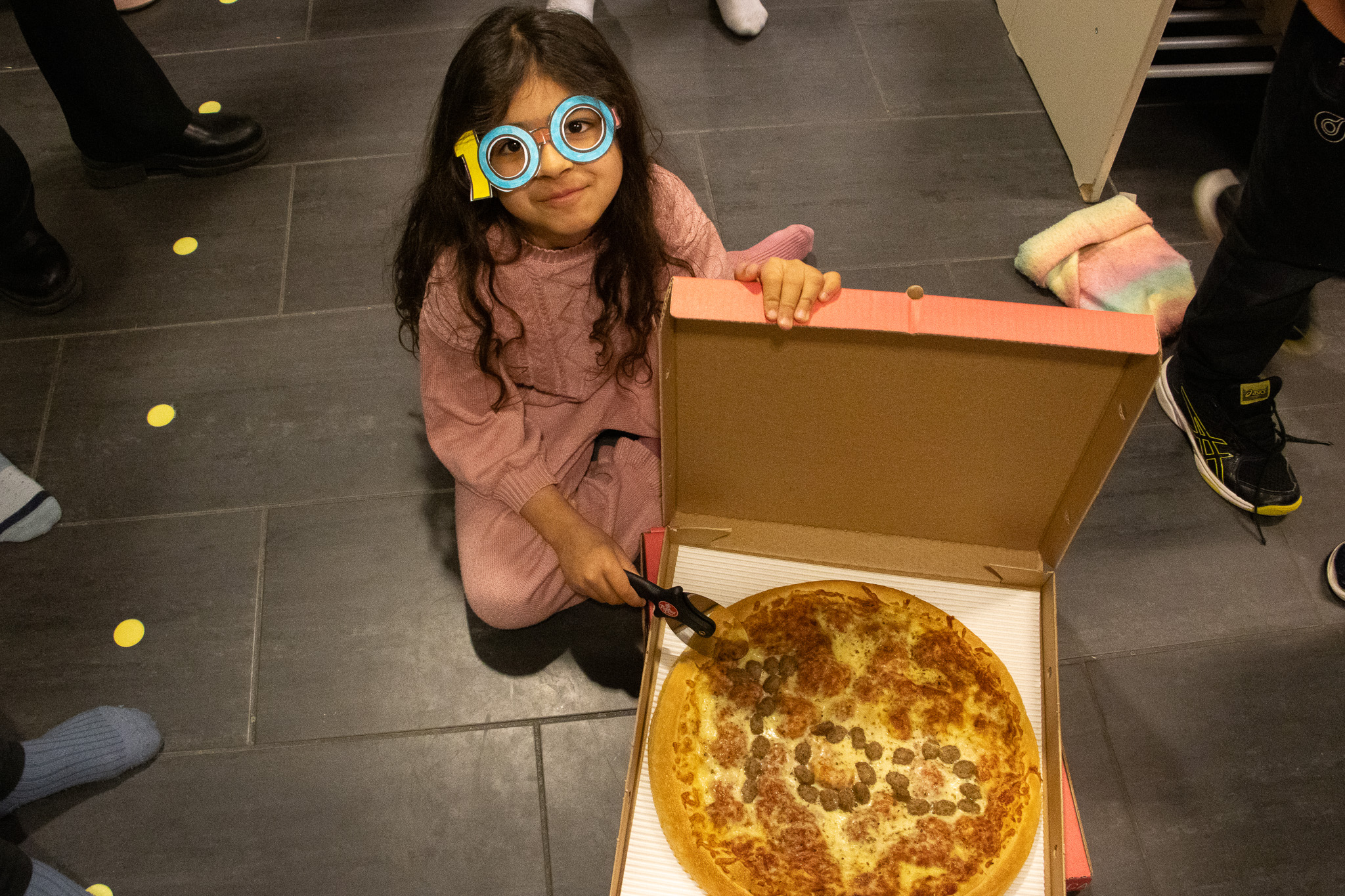 Jente viser frem pizza med tallet 100 på foto. 