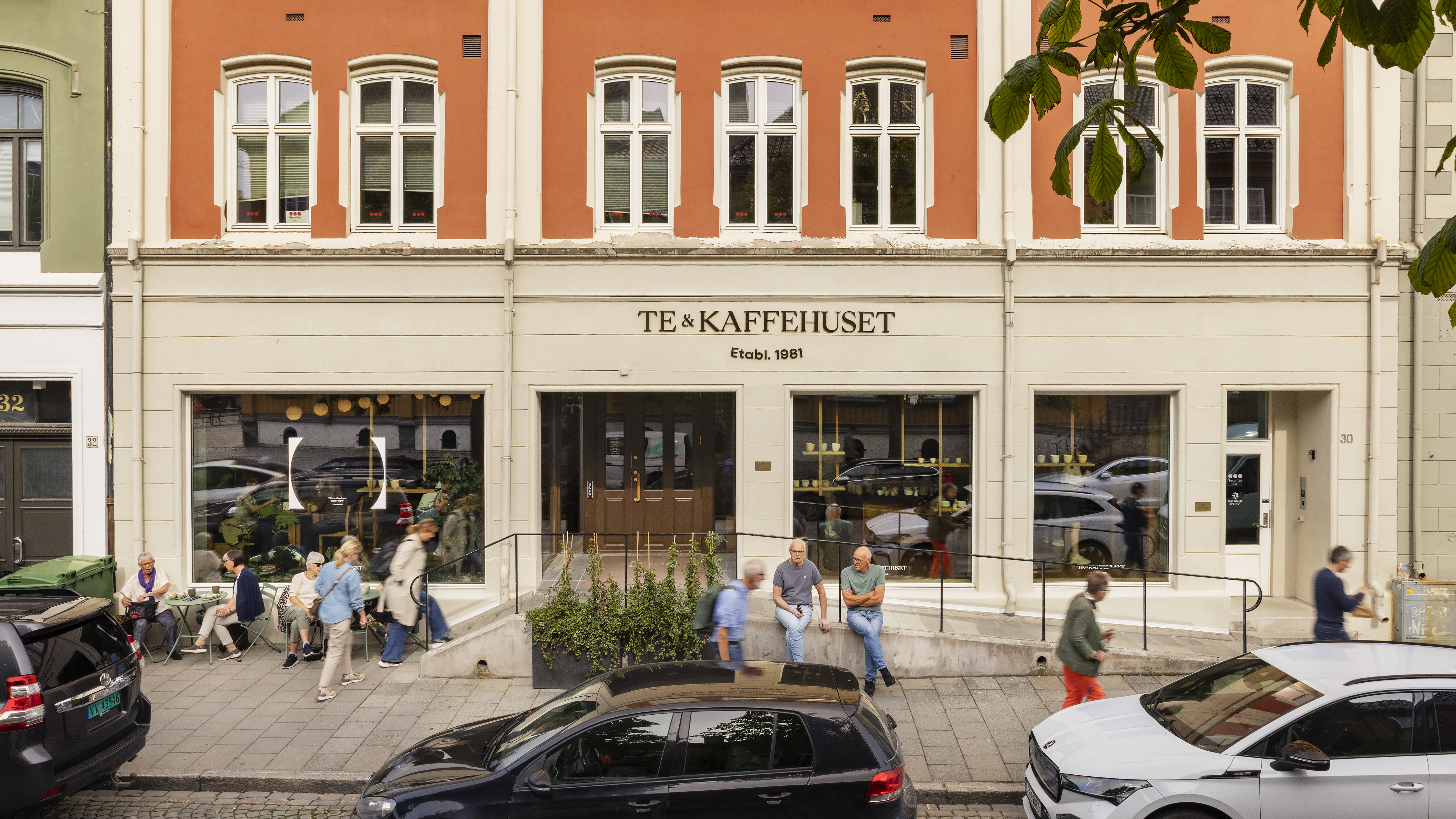 murbygning  i flere etasjer der to vises på foto. Rampe i mur foran bygning