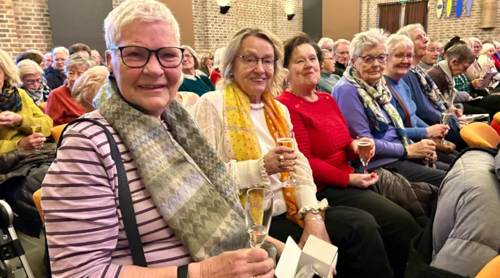 fem kvinner sitter klare til konsert i en stor sal