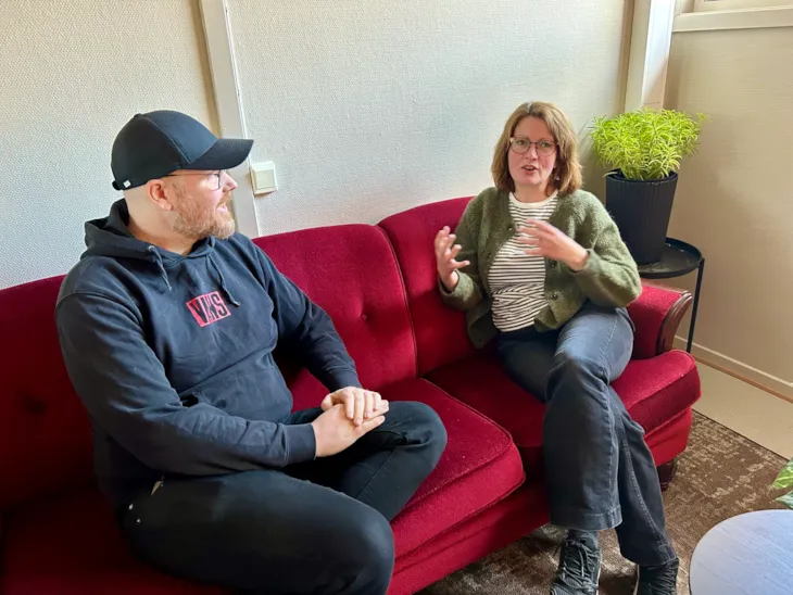 tidgiver og veileder sitter i en rød sofa