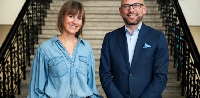 Foto av Michelle Wright og Kristian Dahlberg Hauge stående foran trappen inne i rådhuset i Trondheim