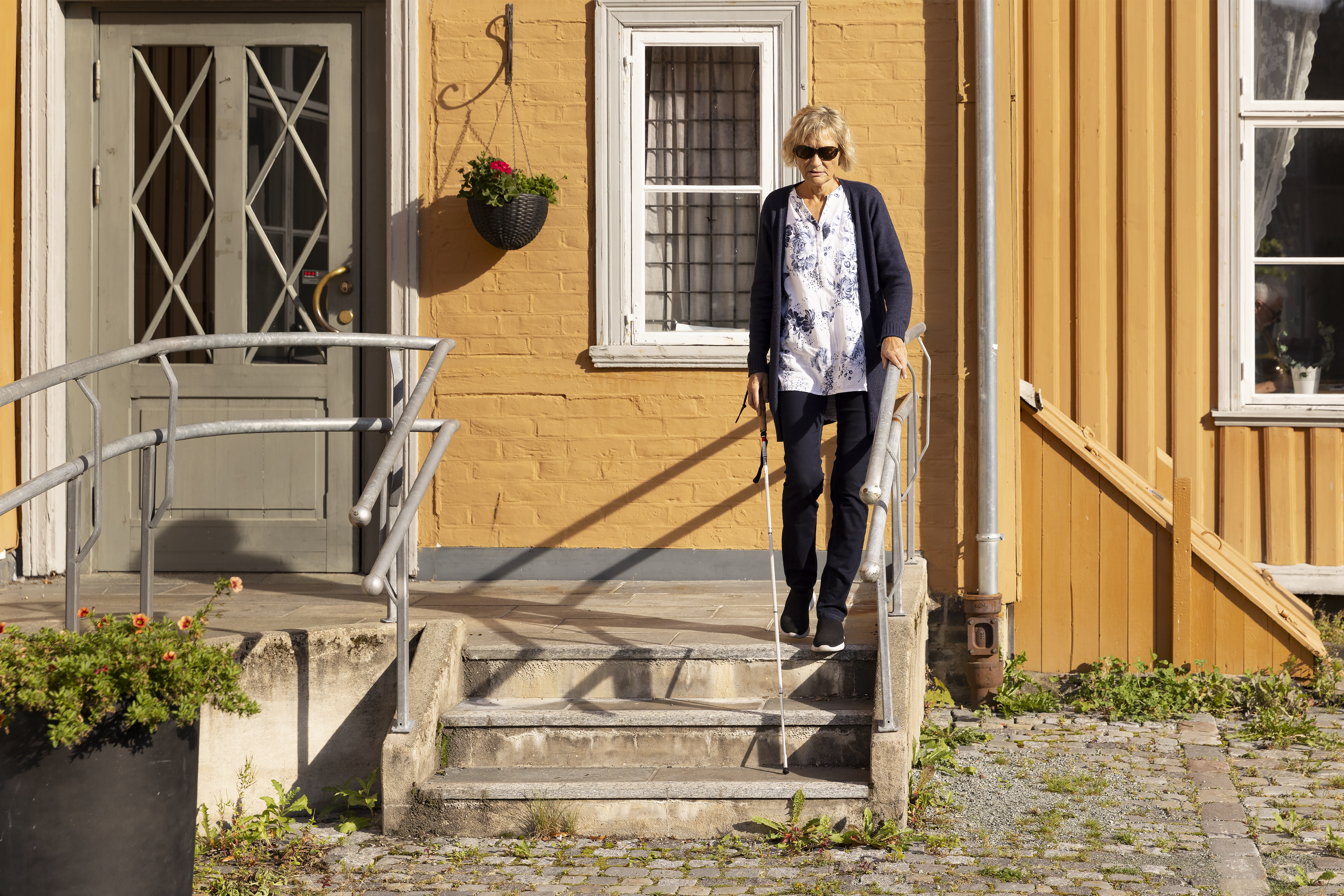 Person med mobilitetsstokk som benytter trappen