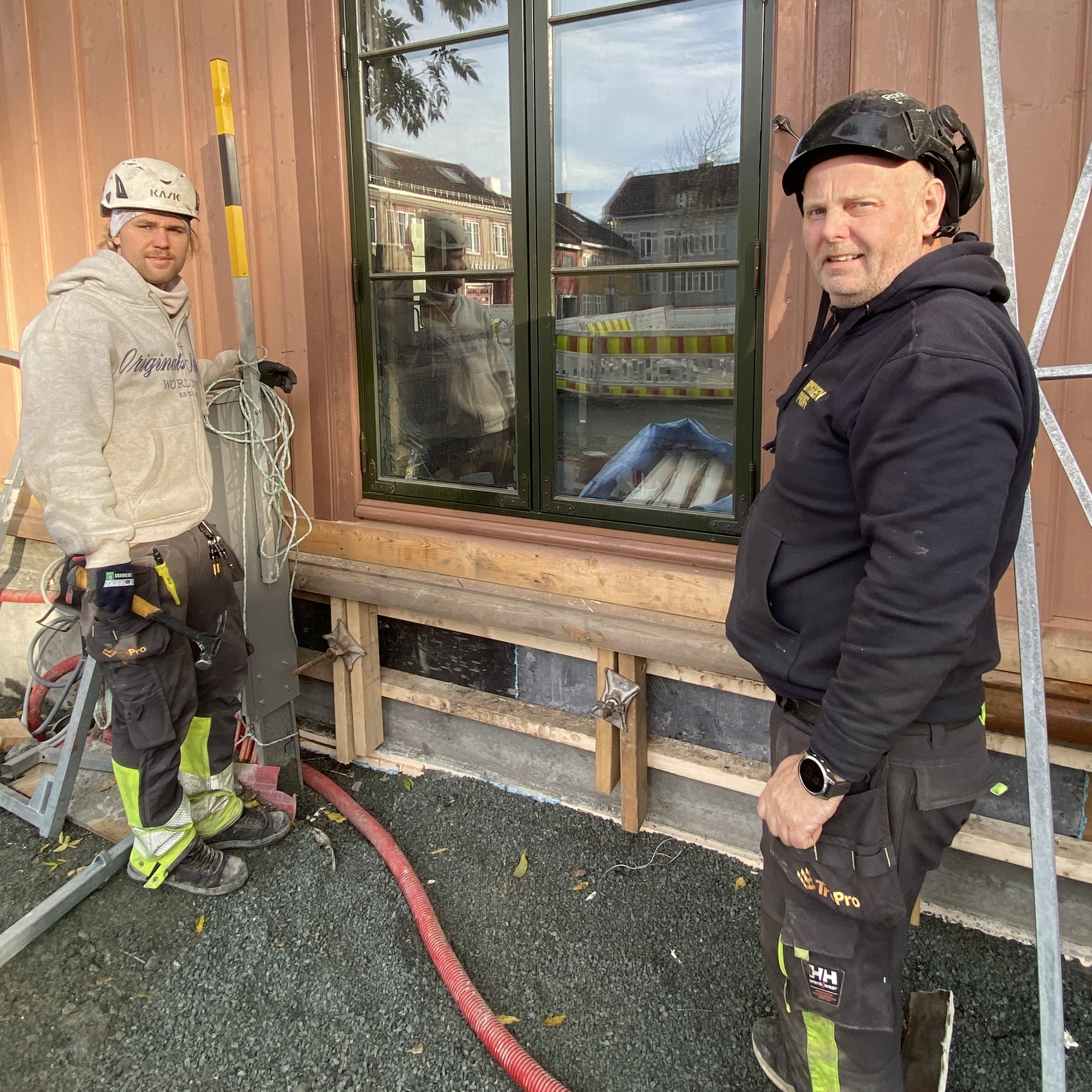 To t&oslash;mrere st&aring;r foran en vegg der det skiftes kledning