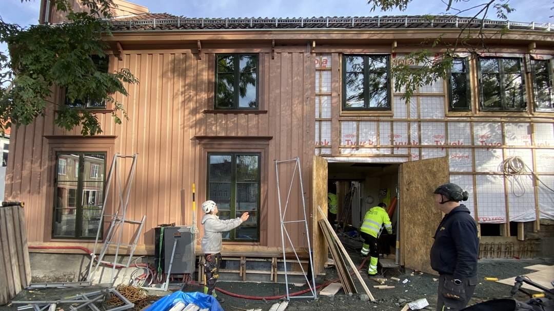 3 håndverkerer arbeider med ny kledning på en fasade på Bakklandet